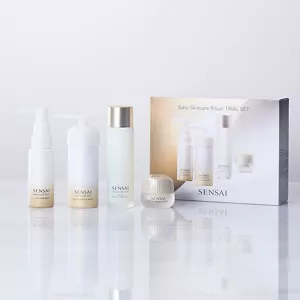 Coffret Découverte SENSAI Rituel de Soin Saho disposé à côté de la boîte du produit sur un fond abstrait blanc.